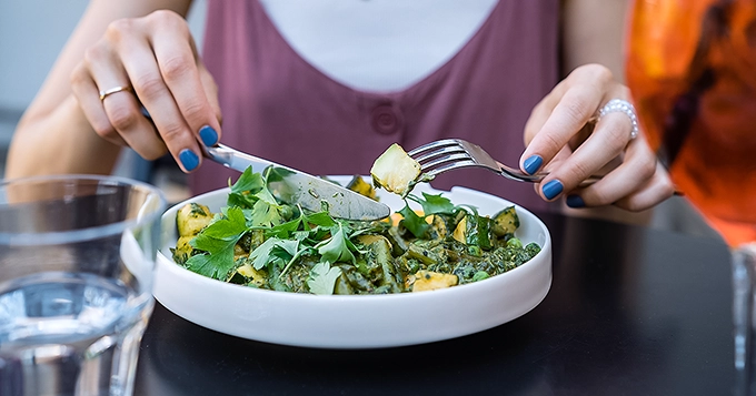 A close-up of a woman eating vegetables | Trainest 