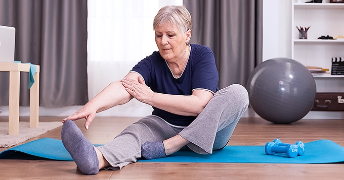 An elderly woman working out at home | Trainest 