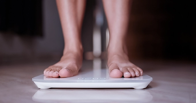 Someone stepping on a smart weight scale | Trainest
