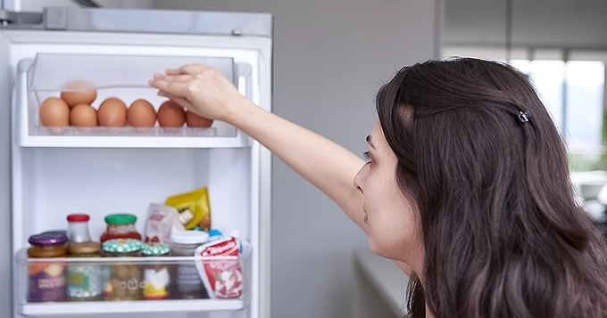 A woman checking for food in the refrigerator | Trainest
