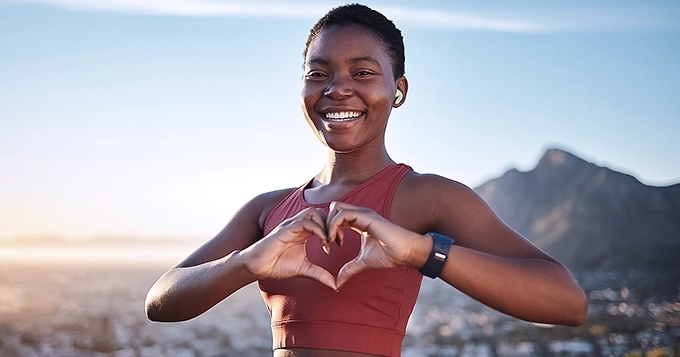 A fit person forming a heart shape with her hands | Trainest