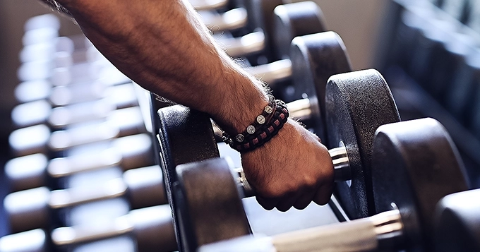 Someone grabbing a dumbbell from the weight rack | Trainest 