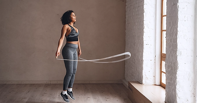 An adult wearing workout attire using a jumping rope | Trainest