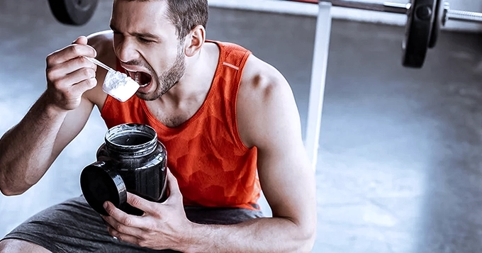 A person in the gym dry scooping a supplement | Trainest
