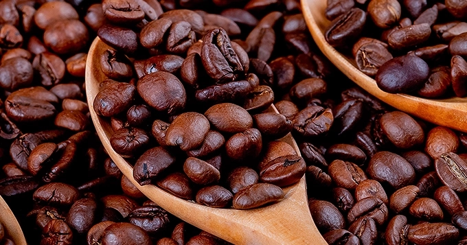 A pile and spoonfuls of roasted coffee beans | Trainest
