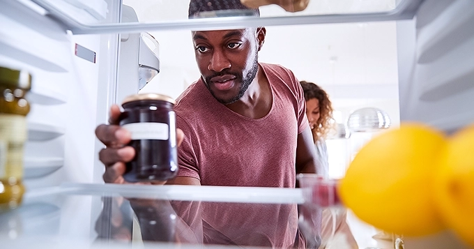 A fit man checking the refrigerator for food | Trainest
