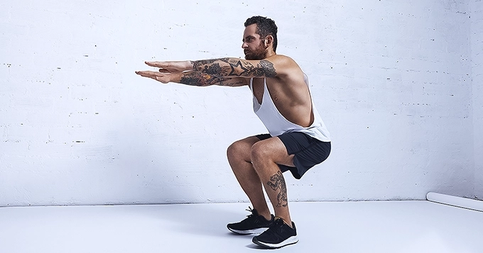 A fit person doing bodyweight squat | Trainest
