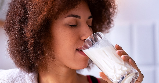 A clos-up photo of a fit person drinking milk | Trainest