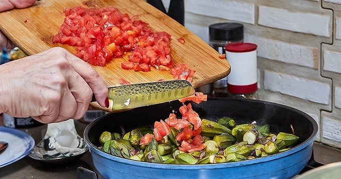 Someone cooking a mix of chopped, vibrantly-colored vegetables | Trainest
