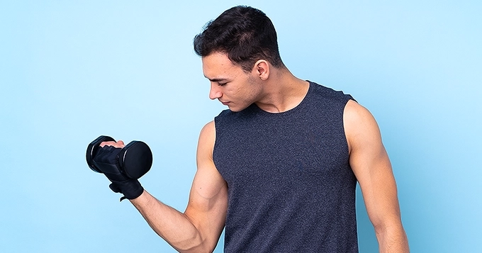 A fit man curling a light dumbbell | Trainest 