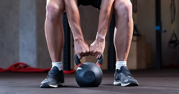 Someone lifting a kettlebell off the floor | Trainest 