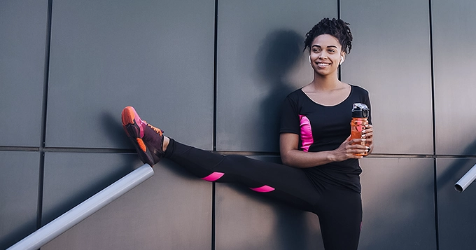 A woman in workout gear stretching her leg | Trainest 