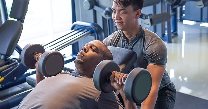 Someone spotting another man while bench pressing | Trainest 