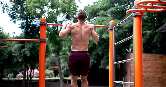 A man showing his back while doing pull-ups | Trainest
