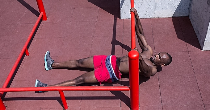 Someone doing horizontal pull-ups in an outdoor gym | Trainest
