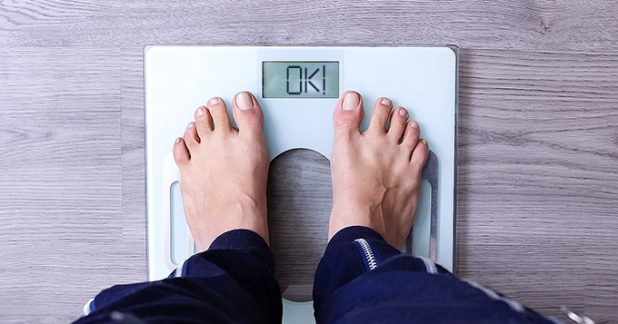 Someone using smart weighing scale and the numbers says 'ok!' | Trainest