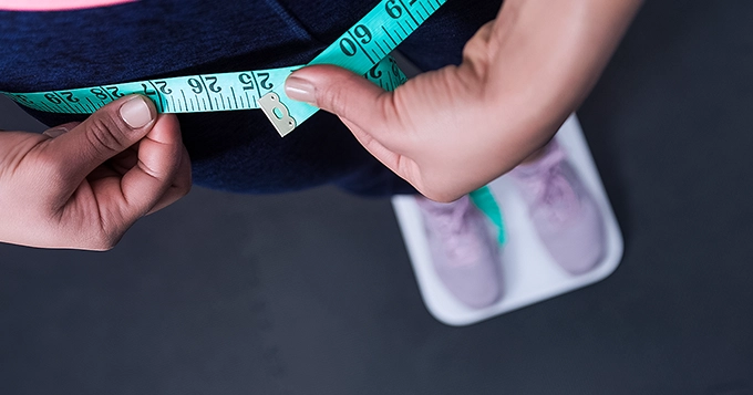 Someone using both smart weighing scale and tape measure | Trainest