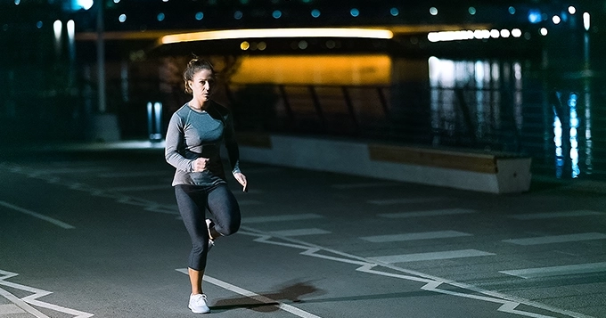 A woman jogging outdoors at night | Trainest 