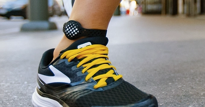 A foot with an ankle fitness tracker | Trainest