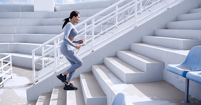 A fit woman running up the stairs, working out | Trainest
