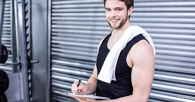 Someone wearing workout clothes while writing on a chart/clipboard | Trainest