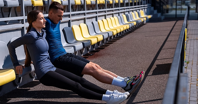 Two people stretching their legs as a warm-up exercise | Trainest