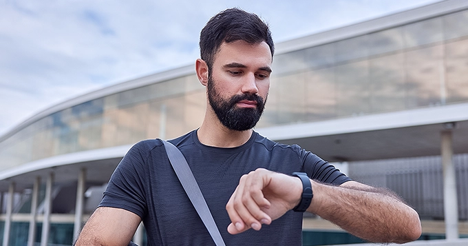 A man looking over his watch outdoors | Trainest