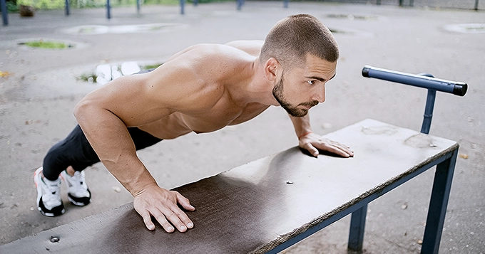 Someone doing incline push-ups outdoors | Trainest