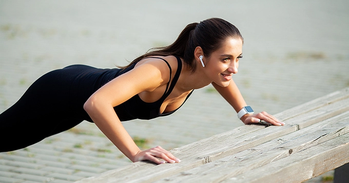 A woman doing incline push-ups outdoors | Trainest