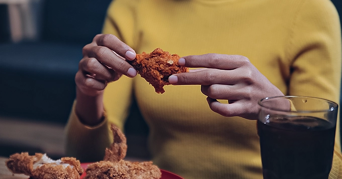 A woman eating fried chicken | Trainest
