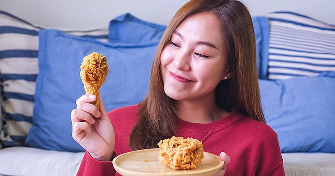 A woman eating fried chicken | Trainest
