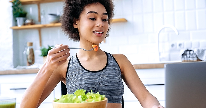 A slim woman eating a healthy meal at home | Trainest
