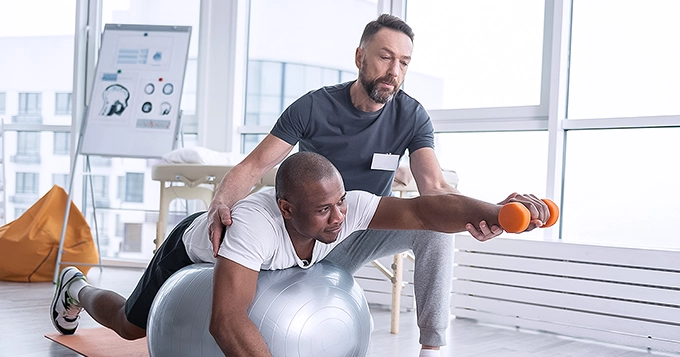 A personal fitness trainer coaching a client inside a gym | Trainest