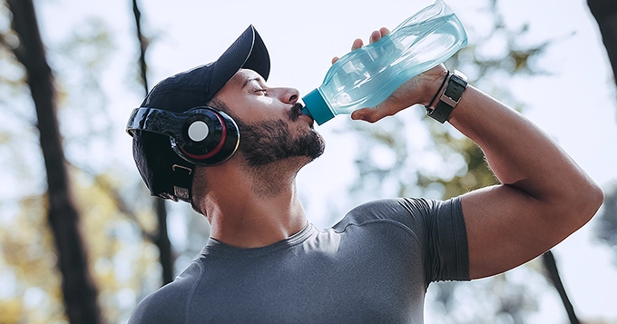 Someone wearing workout clothes while drinking from a water tumbler | Trainest