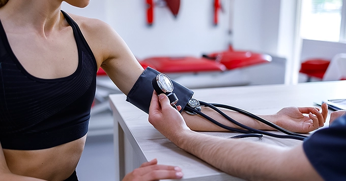 A fit woman getting her blood pressure checked | Trainest
