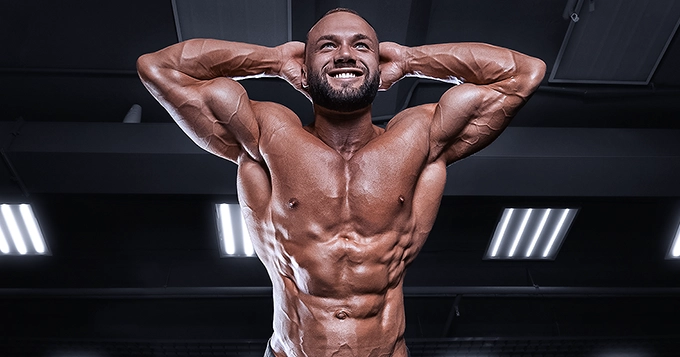 A muscular person flexing his muscle while at the gym | Trainest