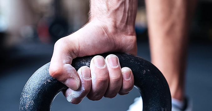 A closeup photo of a hand holding a kettlebell | Trainest