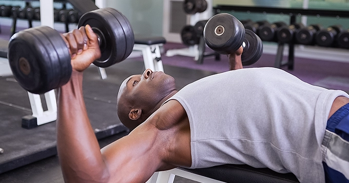 Someone doing dumbbell bench press | Trainest