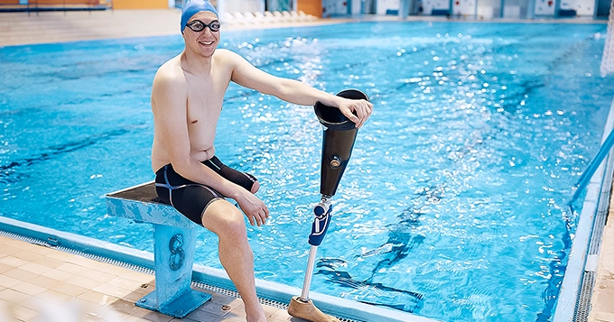 A person with amputated leg at a swimming pool while looking happy | Trainest