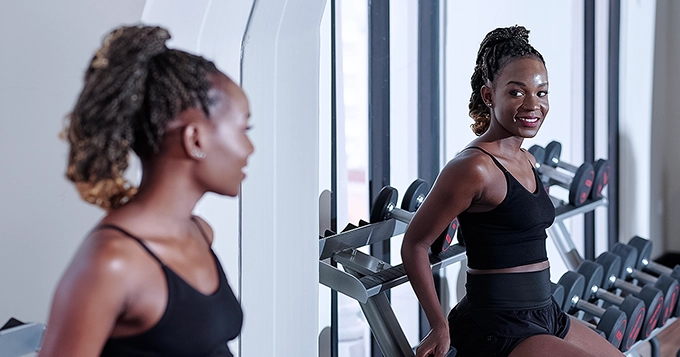 Someone with a fit body posing in front of a mirror in a gym | Trainest