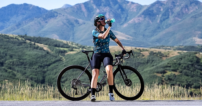 Cyclist drinking from a water bottle outdoors | Trainest