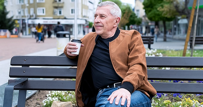 An aged man drinking coffee at the park | Trainest