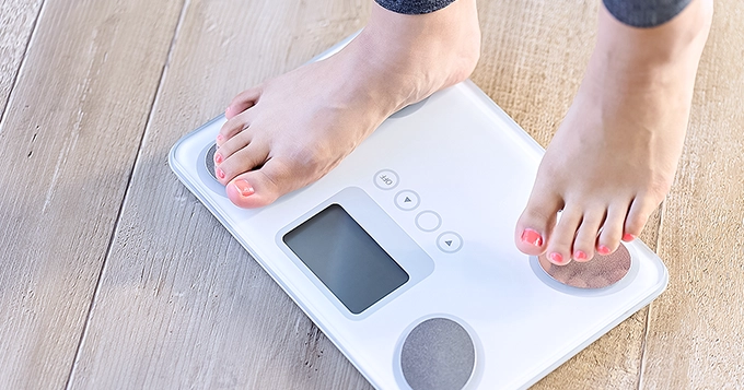 Someone using a smart weight scale | Trainest