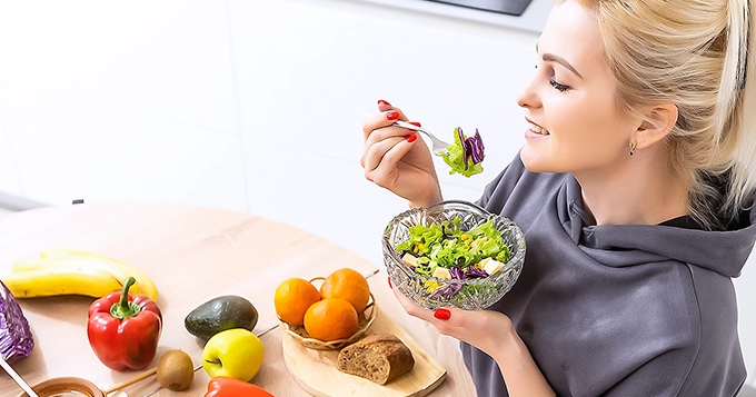 A woman eating a salad | Trainest