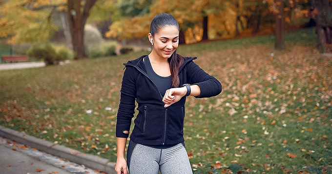 A fit person looking at her smartwatch to track her step count | Trainest